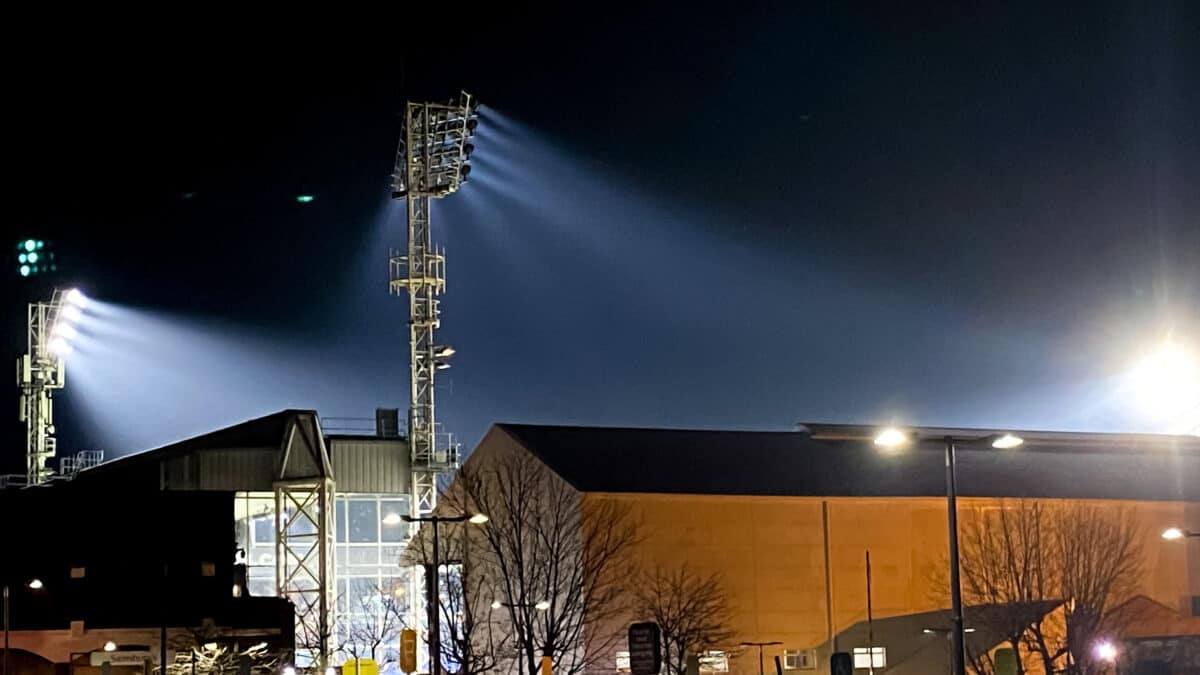 Floodlights above football stands from outside the stadium on a dark night